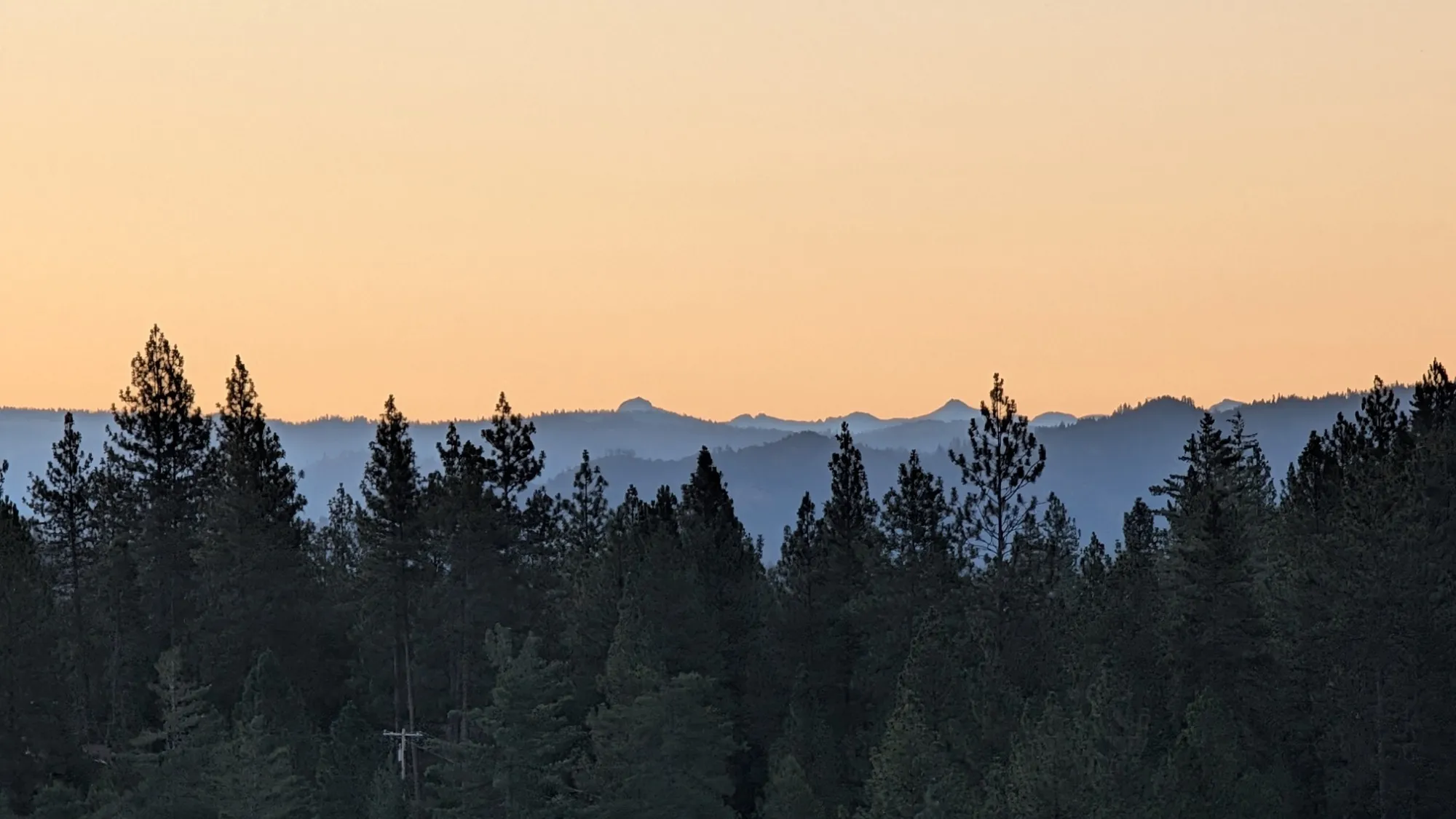 Blue-hour ridgelines under a peach sky