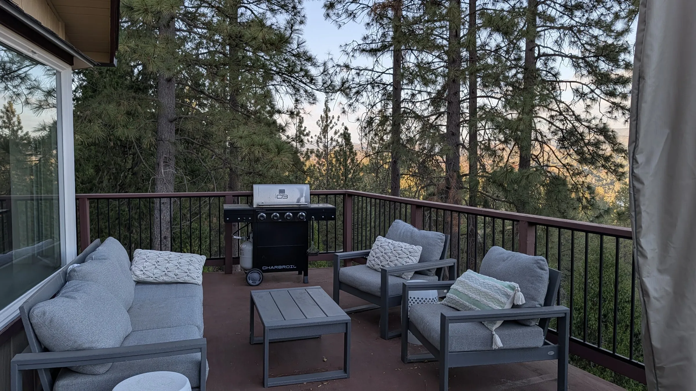 The deck’s outdoor sofa, chairs and coffee table among the pines