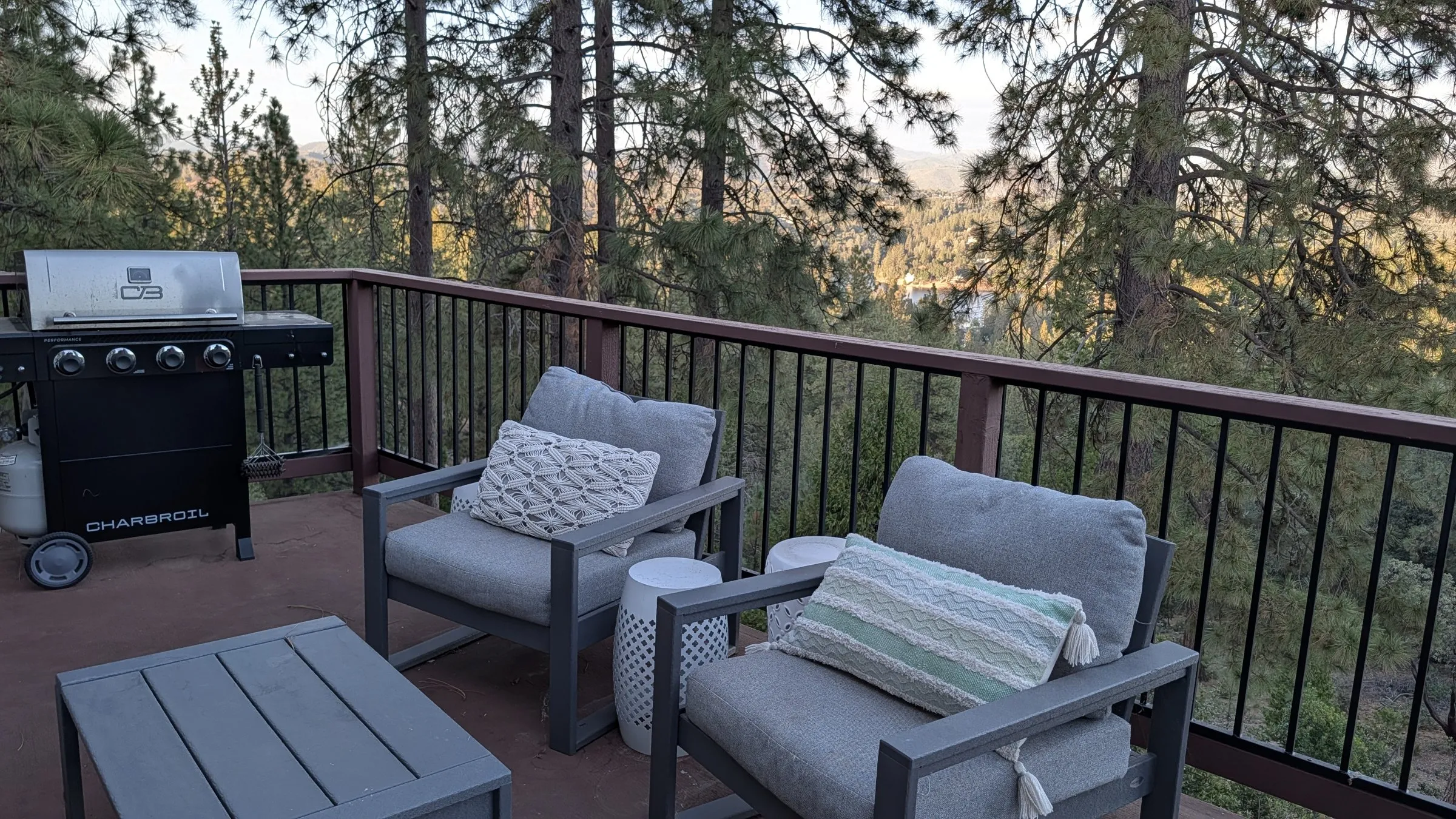 Deck lounge chairs and grill with treetop views