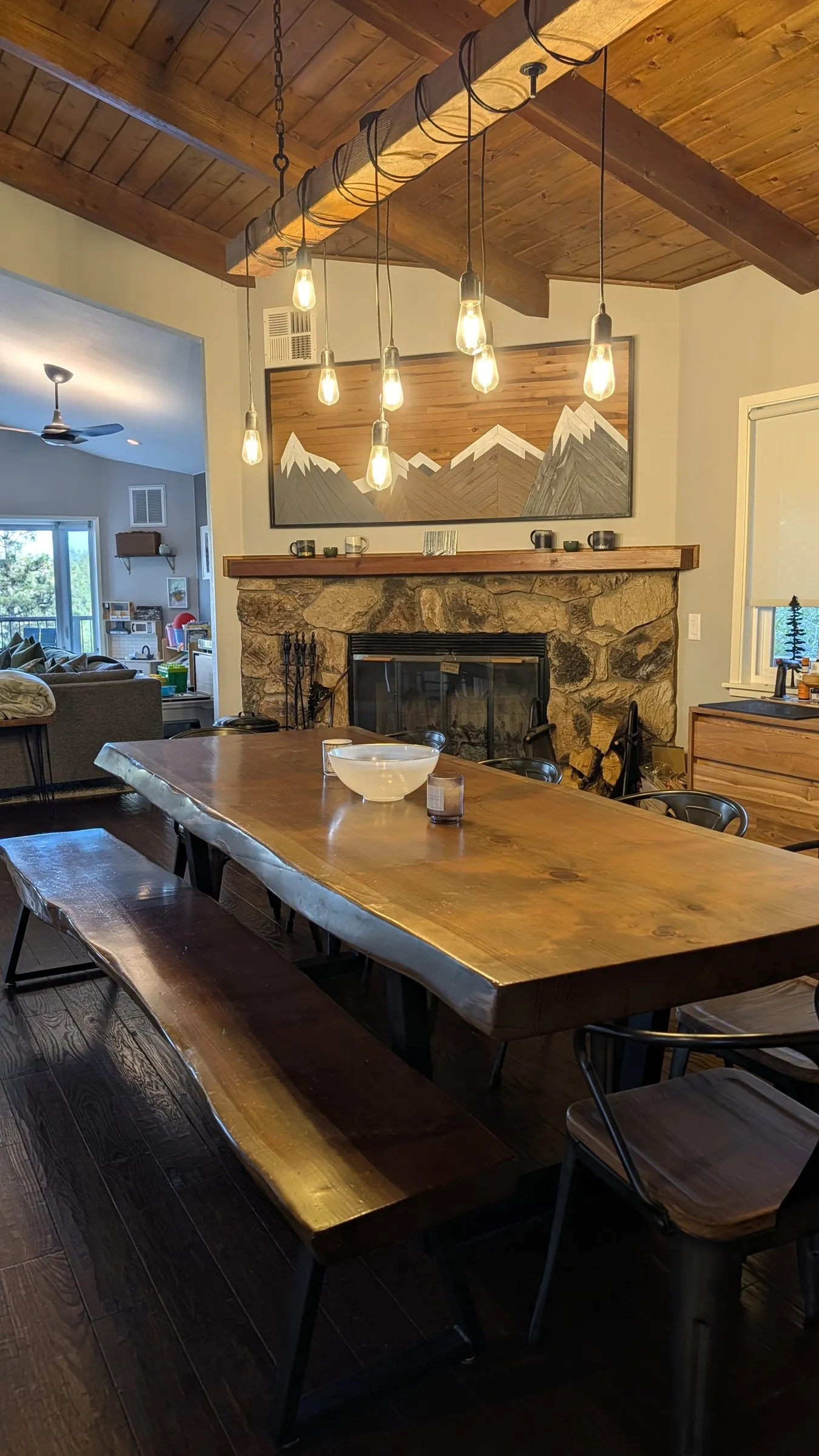 Live-edge dining table in front of the stone wood-burning fireplace