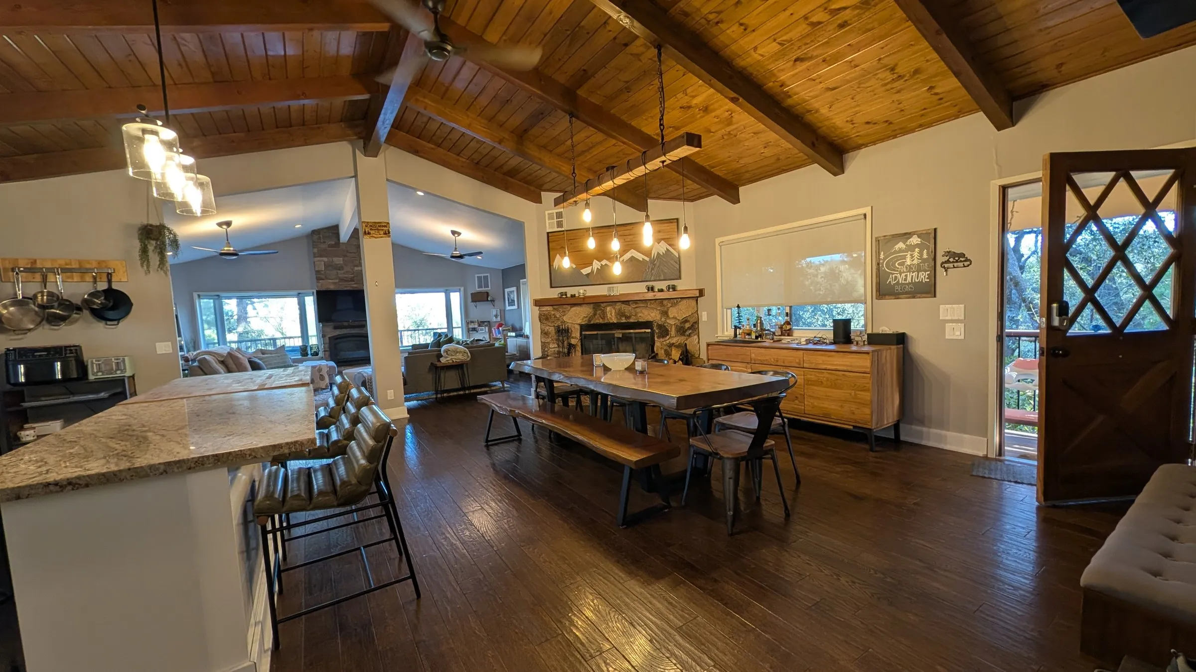 Kitchen island, dining table and stone fireplace under Edison pendants