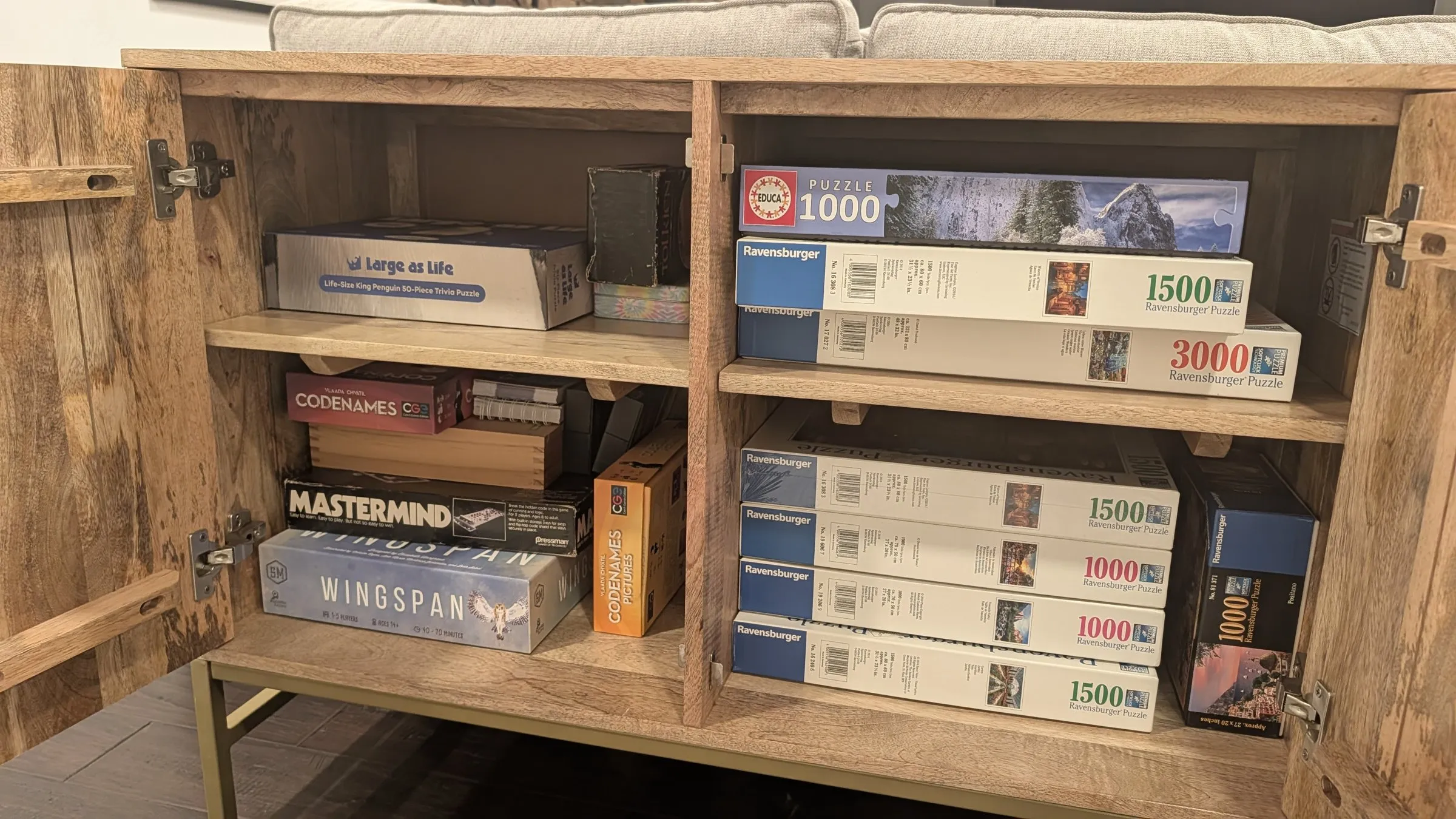 Game cabinet stocked with Wingspan, Codenames, Mastermind and stacks of jigsaw puzzles