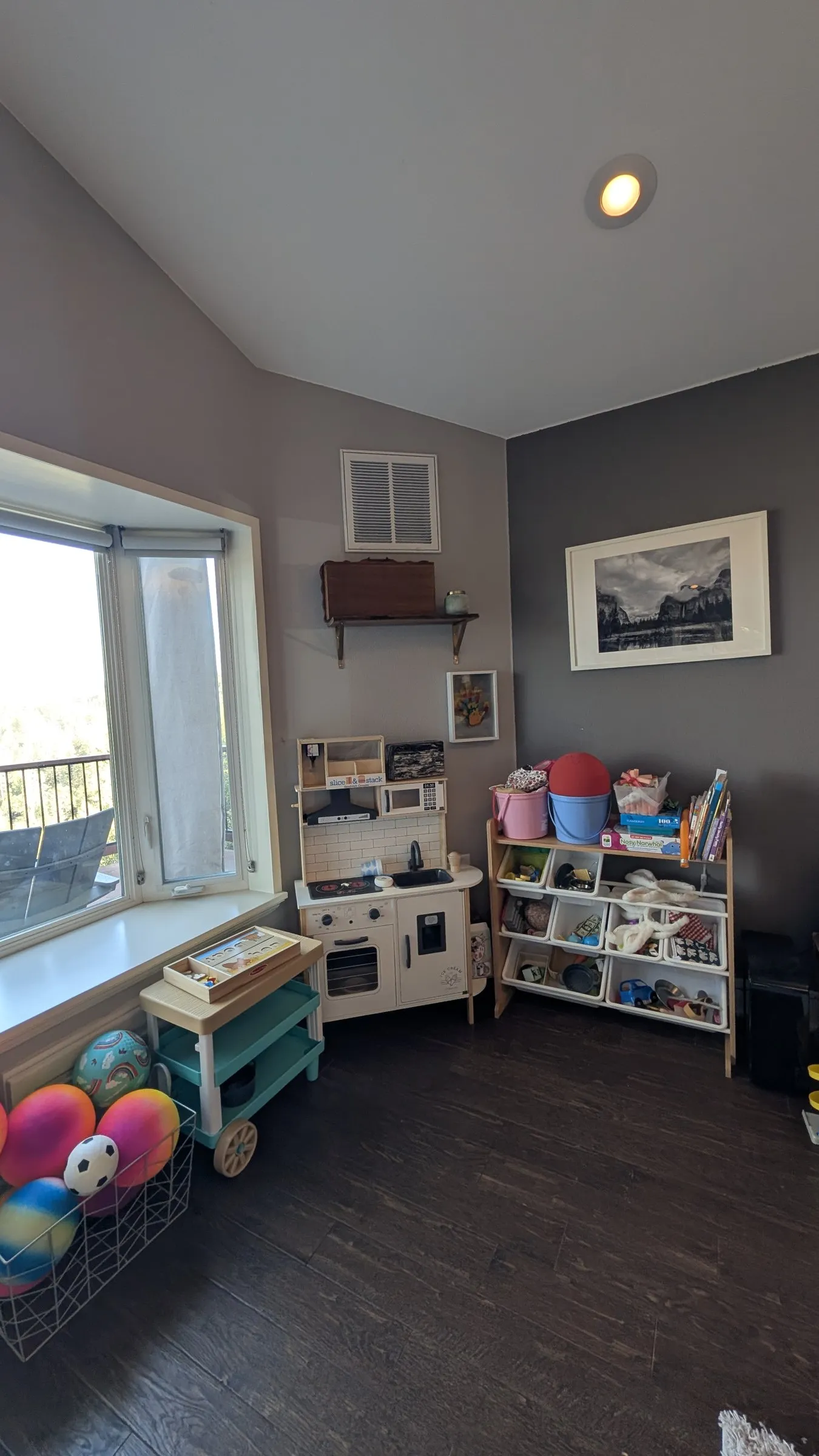 Kids’ play corner in the living room with a toy kitchen, toy bins, books and a basket of balls