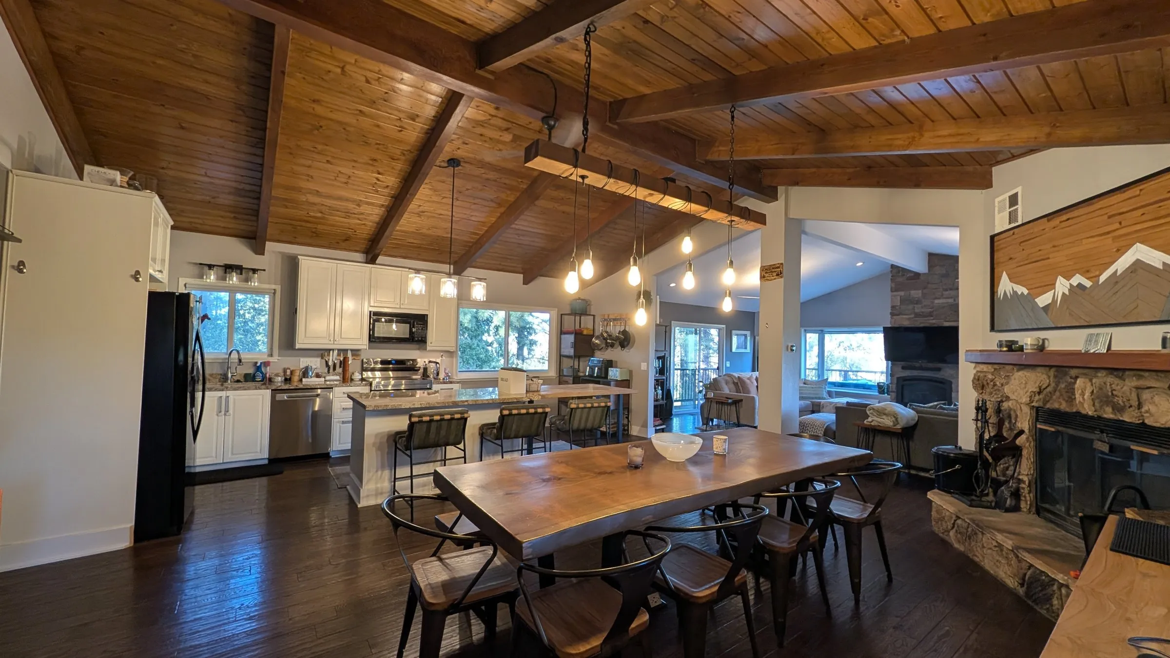 Open kitchen and live-edge dining table under a beamed wood ceiling
