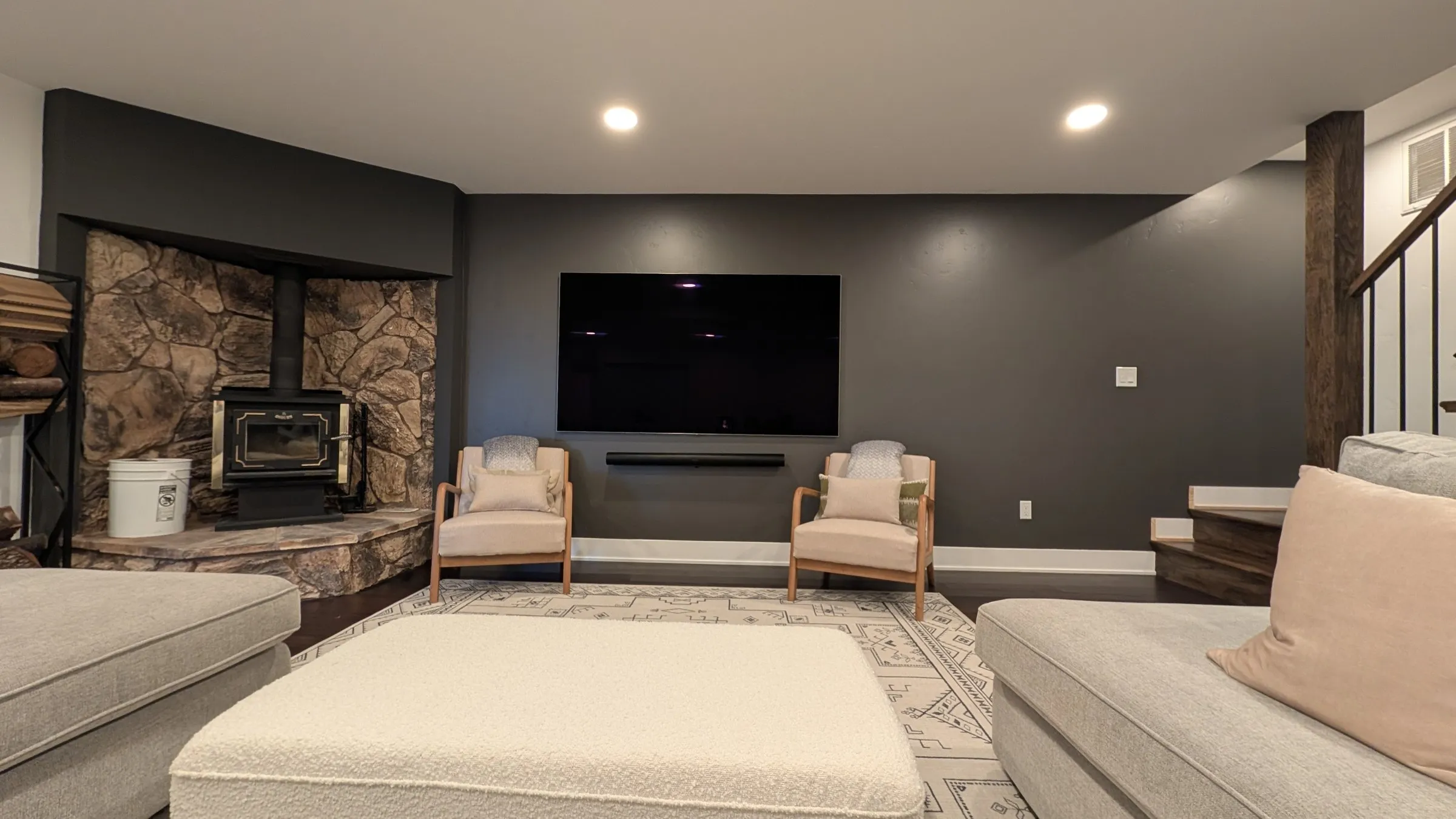Lower-level movie room with big TV and stone wood stove