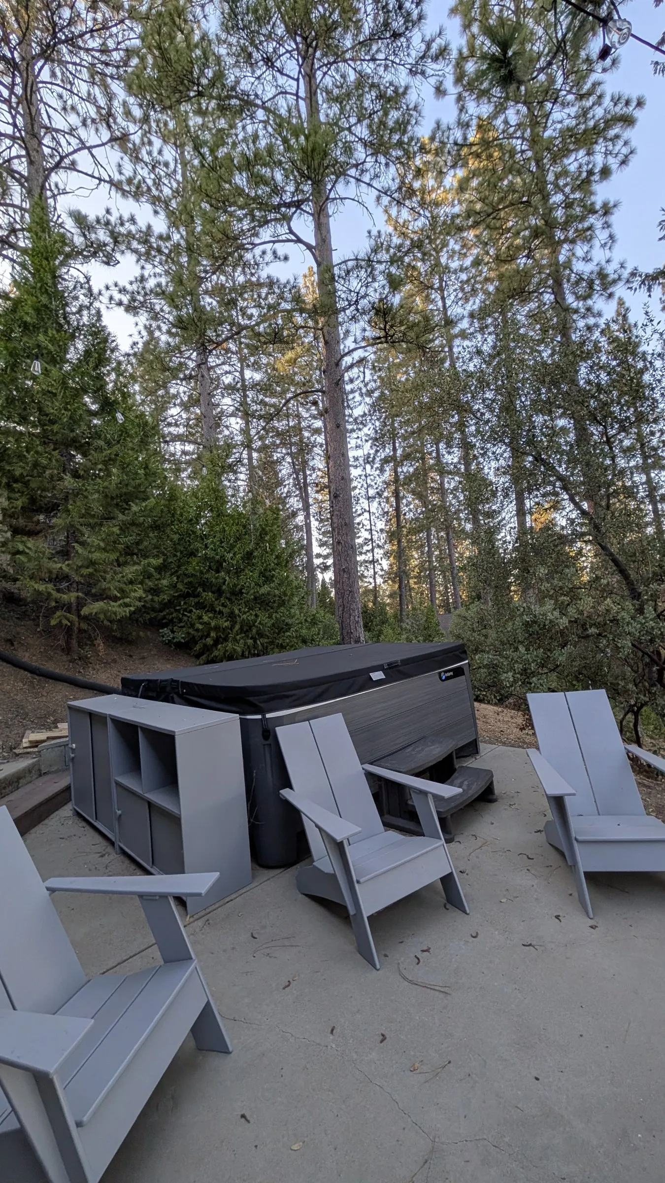 The hot tub on the lower patio, surrounded by tall pines