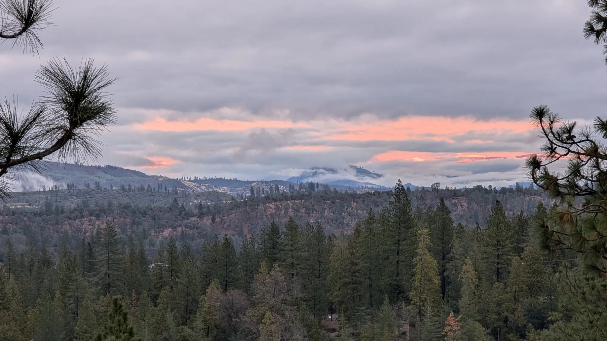 Pink-lit clouds over the far ridges on a winter evening