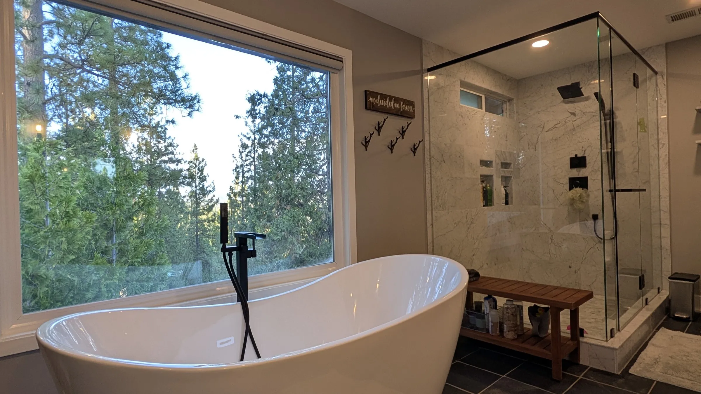 Freestanding soaking tub under a window full of pines